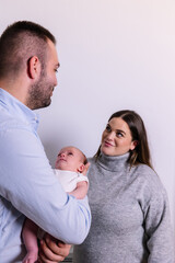 Parents holding newborn baby and looking lovingly at each other