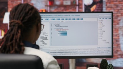 Woman in home office looking at UI on PC screen, typing and executing programming code. Coding application UI used by IT developer writing and testing code in modern apartment, camera B