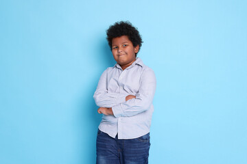 Portrait of cute little boy on light blue background