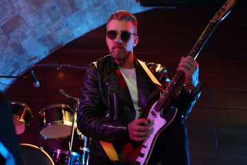 Handsome man playing electric guitar on stage