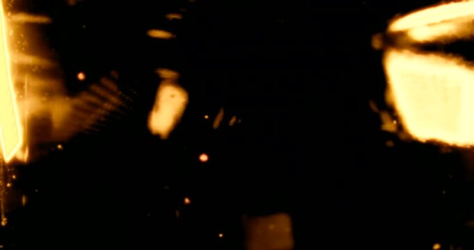 Red and golden particles shimmer in water against a dark background, reflecting warm light like cosmic dust&mdash;glowing, floating, glittering, universe-like atmosphere.