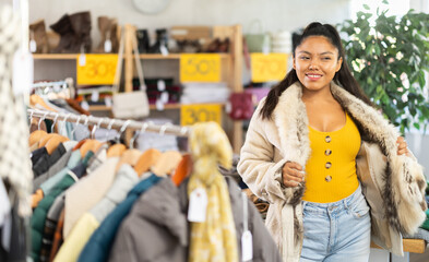 Positive woman tries on a fashionable fur coat in a fashionable clothing store