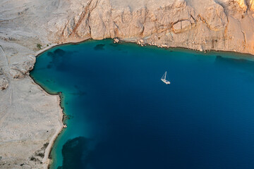 Aerial view of a picturesque bay with a yacht at anchor and islands surrounded by blue sea.