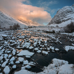 Mountain lake and a snow bank in winter. Loch Achtriochtan. Scottish Highlands
