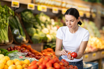 Adult woman buyer choosing fresh tomatoes in vegetable shop
