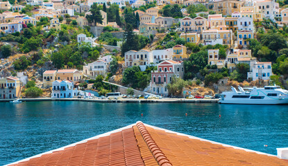 Landscape view on the colorful neoclassical houses and the sea over the roof from the hill, Symi town, Greece