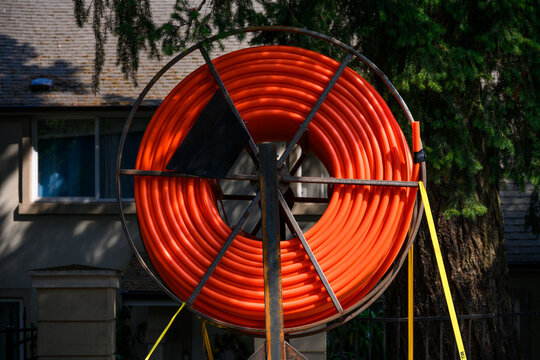 Closeup of large real of bright orange communications conduit, 1 &frac14; inch, SDR, HDPE flexible cable, mounted on the back of a work truck
