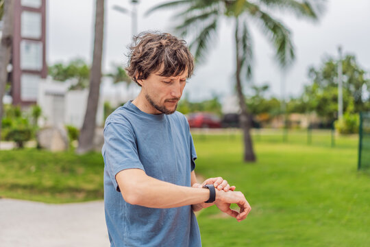Man checking his sports watch during outdoor workout in the park, tracking progress and performance. Concept of fitness, wellness, active lifestyle, health monitoring, and motivation
