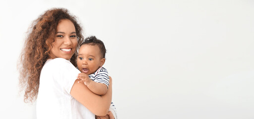 Fototapeta premium Happy African-American mother with cute little baby on white background