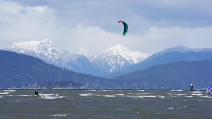 Vancouver, British Columbia, Canada – April 10, 2021 English Bay Windsurfer and Kite Surfer 4K UHD.A wind surfer and kite surfers on English Bay on a windy day. Vancouver, British Columbia, Canada. 4K
