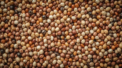 A close-up of numerous peppercorns showing various shades of brown, white, and black.