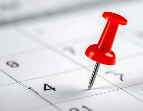 Red pushpin marking a date on a calendar. Symbolizes important appointments, deadlines, planning, and reminders for events or schedules.