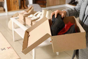 Woman holding paper box with stylish shoes in boutique, closeup