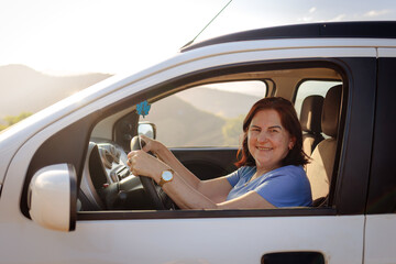 Naklejka premium Confident Brazilian senior woman driving on a sunny road trip, embracing freedom, independence, and active aging while enjoying her journey.