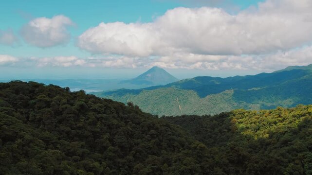 Distant Arenal volcano rising above lush Monteverde cloud forest in Costa Rica