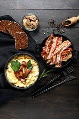 Bowl of tasty banosh, bread, mushrooms and bacon on black wooden background