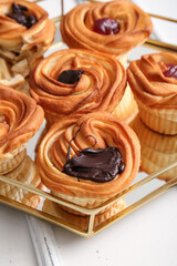 Tray of tasty cruffins with chocolate and jam on white wooden background