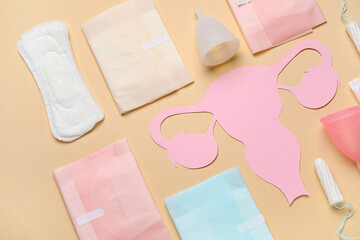 Composition with paper uterus and different feminine hygiene products on color background