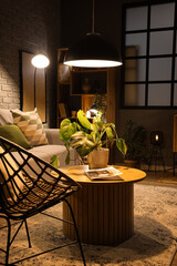 Interior of modern living room with wooden coffee table and glowing lamps at evening