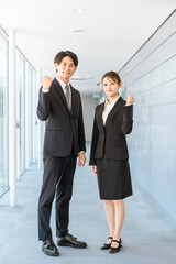 Young Asian businessmen and women in suits standing in an office corridor (fist pump, motivation, expectation, happy)
