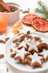 Plate with delicious stars shaped Christmas cookies on light wooden background, closeup
