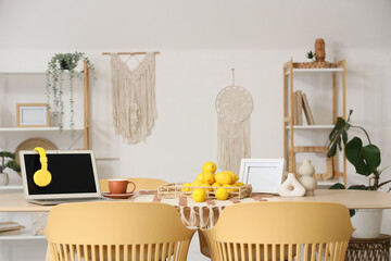 Interior of modern dining room with laptop and fresh lemons on table