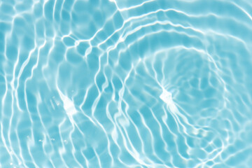 Blue water with ripples on the surface. Defocus blurred transparent blue colored clear calm water surface texture with splashes and bubbles. Water waves with shining pattern texture background.