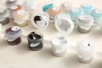Paints for painting by numbers on white wooden background, closeup