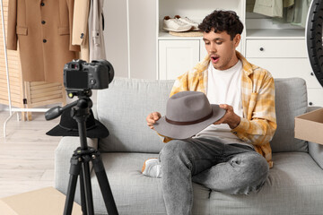 Male blogger with felt hat recording video on sofa at home