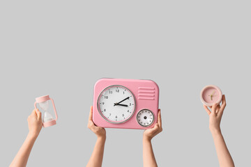 Female hands holding different clocks on grey background