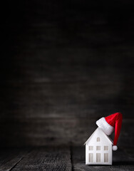 Santa Claus hat on model of house, closeup. Isolated on wooden background. Christmas celebration. Winter holidays