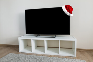 Santa Claus Hat on Lcd tv on white shef at modern room interior. Christmas and New Year celebration