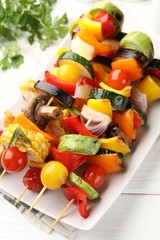 Skewers with tasty grilled vegetables and parsley on white wooden table, closeup