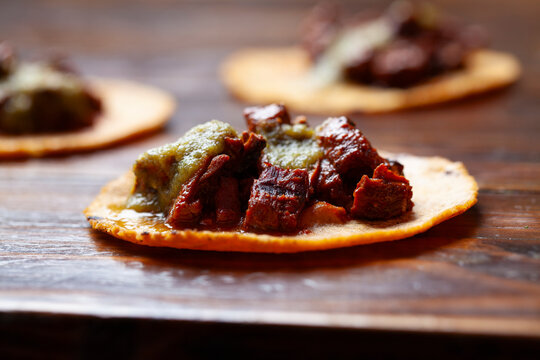 A close-up shot of a grilled carne asada street taco with green salsa verde on a corn tortilla, sitting on a wooden table. - Powered by Adobe