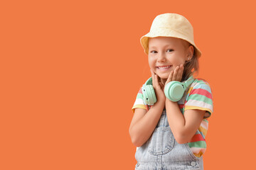 Cute little girl with headphones on orange background