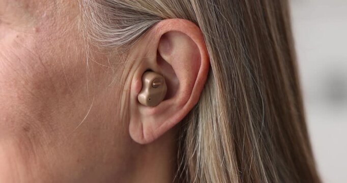 Senior woman with hearing aid at home, closeup