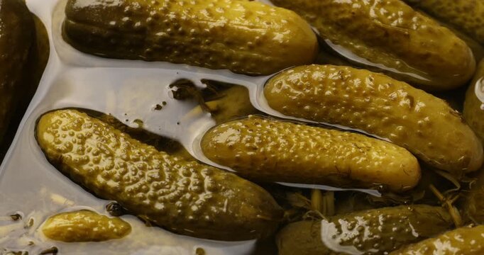 Closeup view of pickled cucumbers in brine as background, spinning