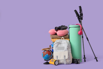 Walking poles, backpack and hiking equipment on lilac background