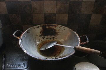 A close-up, abstract shot of a rusty, weathered metal surface, possibly a pot or drum edge, with dark, moody lighting. The image highlights texture, decay, and industrial elements