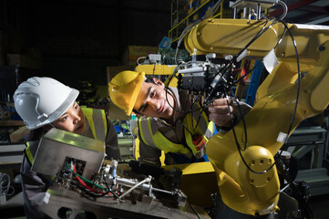 Engineer robot arm maintenance teamwork safety helmet workshop machinery automation factory scene with engineers adjusting industrial robot arm under bright light showing focus and precision