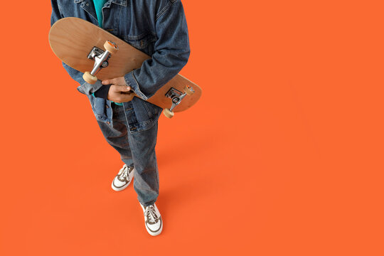 Young man with skateboard on orange background, closeup - Powered by Adobe