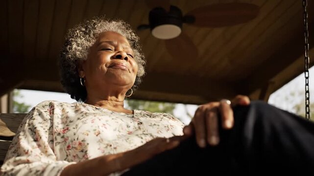 Woman relaxing on porch swing in golden sunlight with eyes closed