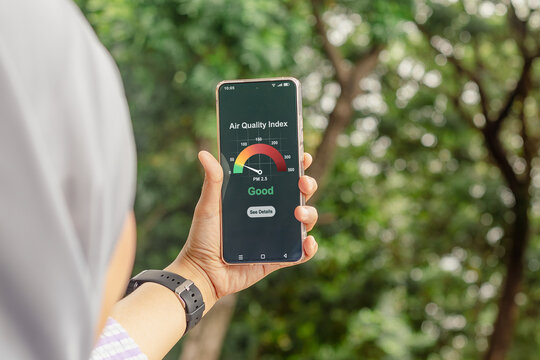 A young Muslim woman checking the outdoor air quality index using an app on her smartphone