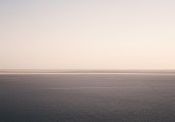 Fototapeta premium An expansive, empty landscape where the flat horizon creates a perfect, unbroken line separating the pale sky from the smooth, endless terrain, subtle, empty, sky