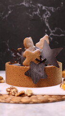 Delicious chocolate tart decorated with star and leaf cookies, walnuts, and cape gooseberries on a marble background. Perfect for holiday dessert, bakery presentation, or festive food photography
