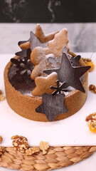 Delicious chocolate tart decorated with star and leaf cookies, walnuts, and cape gooseberries on a marble background. Perfect for holiday dessert, bakery presentation, or festive food photography