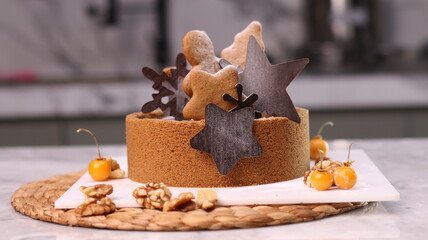 Delicious chocolate tart decorated with star and leaf cookies, walnuts, and cape gooseberries on a marble background. Perfect for holiday dessert, bakery presentation, or festive food photography