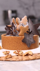Delicious chocolate tart decorated with star and leaf cookies, walnuts, and cape gooseberries on a marble background. Perfect for holiday dessert, bakery presentation, or festive food photography