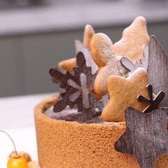 Delicious chocolate tart decorated with star and leaf cookies, walnuts, and cape gooseberries on a marble background. Perfect for holiday dessert, bakery presentation, or festive food photography