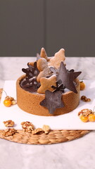Delicious chocolate tart decorated with star and leaf cookies, walnuts, and cape gooseberries on a marble background. Perfect for holiday dessert, bakery presentation, or festive food photography
